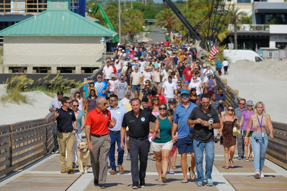 Jacksonville Mayor Lenny Curry and other government officials lead a crowd of beachgoers up the new incline of the rebuilt Jacksonville Beach Pier after a ribbon-cutting ceremony Wednesday morning. The pier is now open during the day for pedestrians but will not be open for fishing for another two weeks.