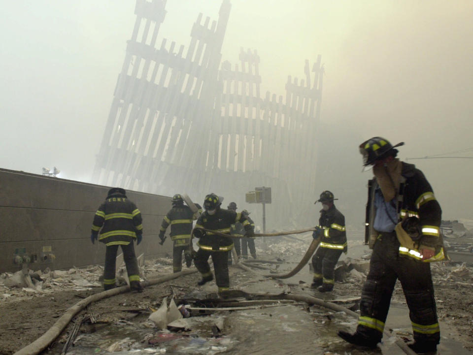 <p>With the skeleton of the World Trade Center twin towers in the background, New York City firefighters work amid debris on Cortlandt Street after the terrorist attacks in this Sept. 11, 2001, photo. (Photo:Mark Lennihan/AP) </p>