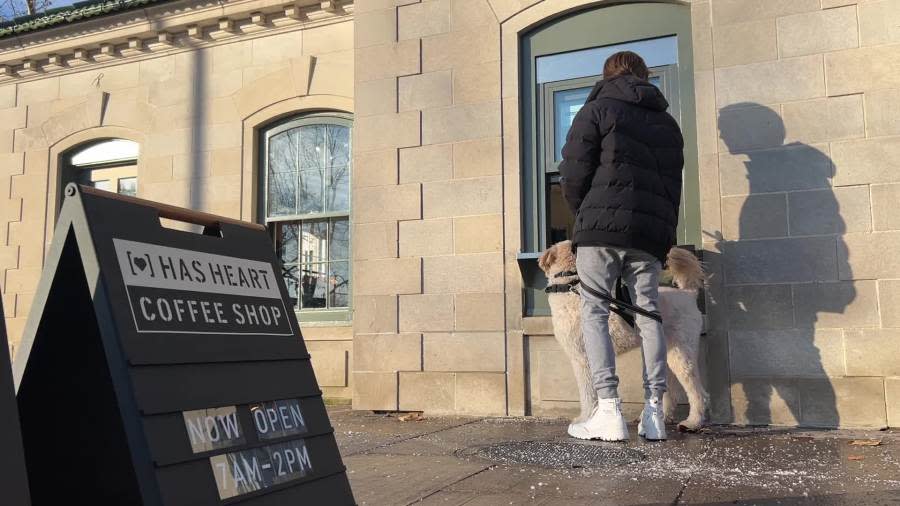 A customer and his dog ordering coffee from the HAS HEART coffee shop’s walk-up window. (December 3, 2023)