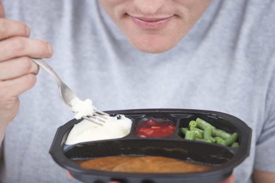 young man eating tv dinner, mid section