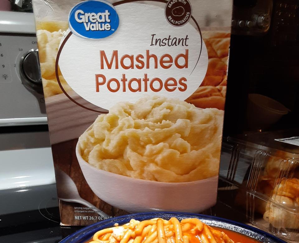 A box of instant mashed potatoes next to a bowl of spaghetti