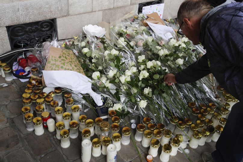 A man places a flower to pay tribute to French teacher Dominique Bernard during his funeral, in Arras, northern France, Thursday, Oct. 19, 2023.