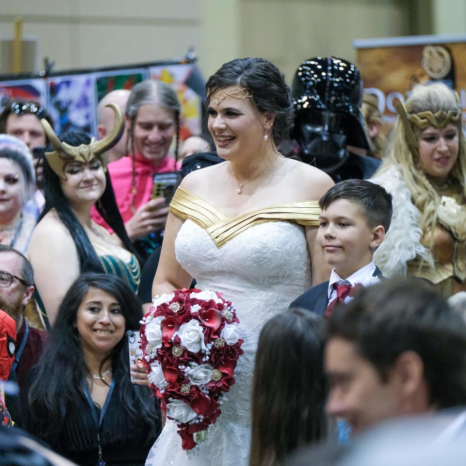 Katie Whittaker aka Capital City Wonder Woman, walks down the aisle at her wedding at Capital City Comic Con at the Lansing Center Sunday, July 10, 2022.