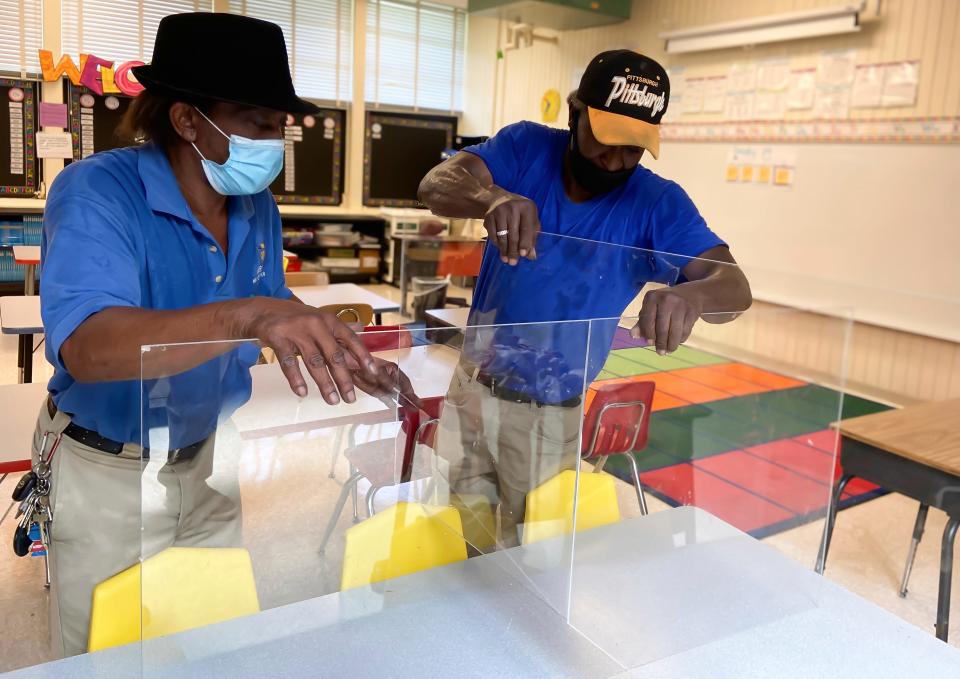 Tommy Croft and Eddie Ford install plexiglass dividers on desks in a classroom at Oakland Heights Elementary School in Meridian, Miss.