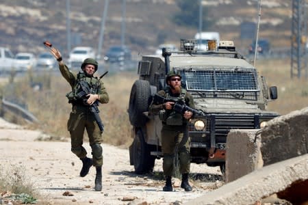 Israeli soldier hurls a sound grenade towards Palestinian demonstrators during a protest against Bahrain's workshop for U.S. peace plan, near the Jewish settlement of Beit El, in the Israeli-occupied West Bank