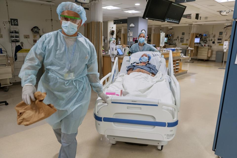 CORRECTS LAST NAME TO VLASSAKOV - In this July 28, 2020, photo released by Brigham and Women's Hospital, members of the transplant anesthesiology team, Drs. Kamen V. Vlassakov front, and Lindsay Wahl lead Carmen Blandin Tarleton to the operating room for her second face transplant at Brigham and Women's Hospital in Boston. Tarleton, who had her first face transplant in 2013, became the first American and only the second person globally to undergo a second face transplant procedure after her first transplant failed. (J. Kiely Jr./Lightchaser Photography/Brigham and Women's Hospital, via AP).