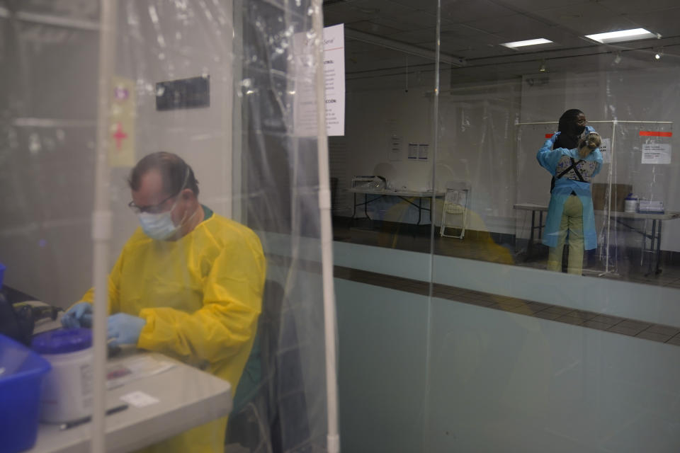 Registered nurse Leslie Clark, right, collects a nasal swab sample from a mans as administrative worker Sander Edmondson works on his computer at a COVID-19 testing site in Los Angeles, Sunday, Dec. 27, 2020. Hospitals in central and Southern California are quickly running out of intensive care unit beds for coronavirus patients and state officials are poised to extend the strictest stay-at-home orders there as conditions worsen before the post-holiday surge hits. (AP Photo/Jae C. Hong)