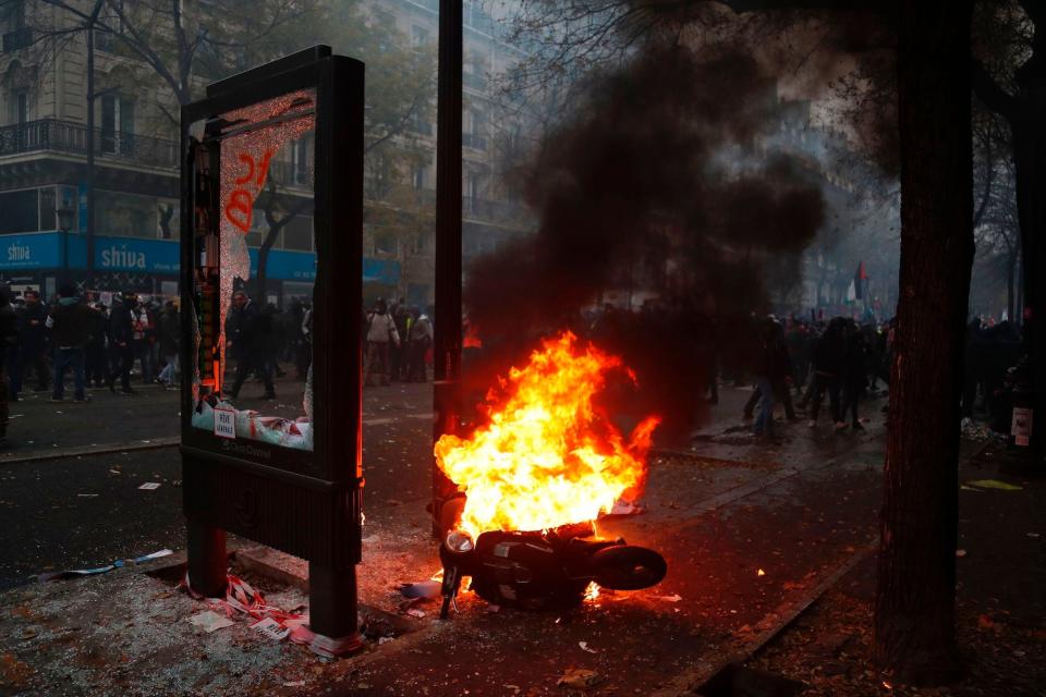  A broken electronic billboard is seen next to a burning scooter as protesters stand in the back during a rally against the pension overhauls, in Paris, on December 5, 2019 as part of a nationwide strike. 