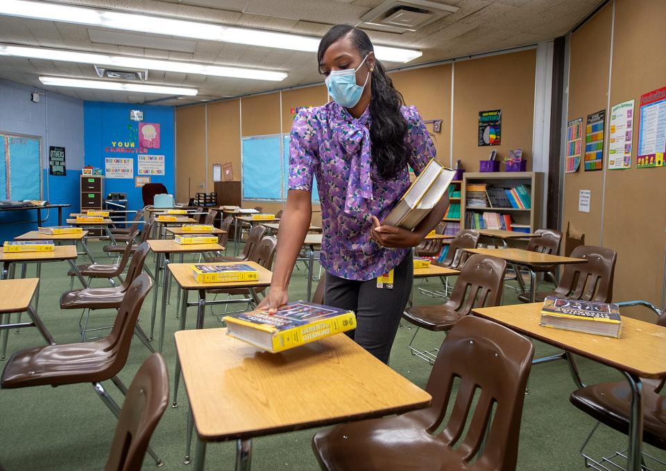 English/language arts teacher Malikah Upchurch places a textbook on each student's desk in her classroom at Armstrong Middle School in Fairless Hills, Pa., in September 2021.