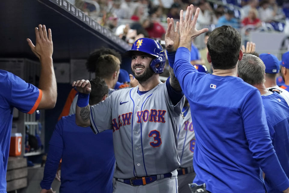 New York Mets' Tomas Nido (3) is congratulated in the dugout after scoring on a double by Francisco Lindor during the sixth inning of the team's baseball game against the Miami Marlins, Friday, June 24, 2022, in Miami. (AP Photo/Lynne Sladky)