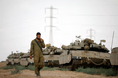 An Israeli soldier walks next to military armoured vehicles gathered in an open area near Israel's border with the Gaza Strip October 18, 2018. REUTERS/Amir Cohen