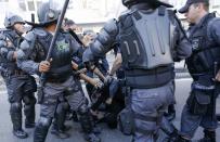 A demonstrator (C, rear) is detained by riot police before the 2014 World Cup final match between Argentina and Germany in Rio de Janeiro, July 13, 2014. REUTERS/Marco Bello (BRAZIL - Tags: POLITICS SOCCER CRIME LAW SPORT CIVIL UNREST WORLD CUP)