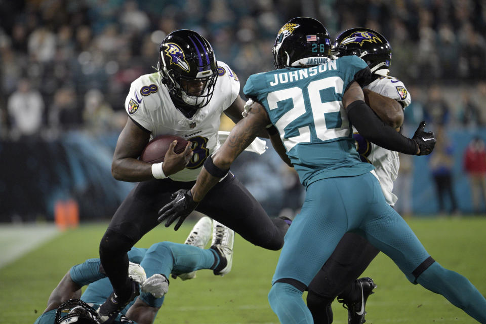 Baltimore Ravens quarterback Lamar Jackson (8) scrambles against Jacksonville Jaguars safety Antonio Johnson (26) in the first half of an NFL football game Sunday, Dec. 17, 2023, in Jacksonville, Fla. (AP Photo/Phelan M. Ebenhack)