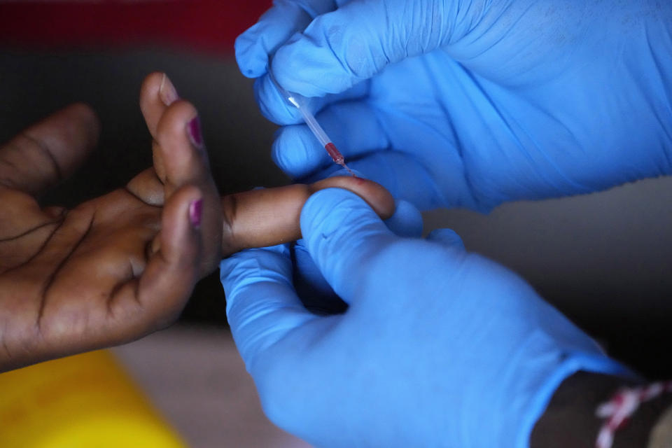 Shadrack Mashabane, curandero tradicional, toma una muestra de sangre para una prueba rápida de detección del VIH en su choza en Bushbuckridge, Sudáfrica, el 9 de mayo de 2024. (AP Foto/Themba Hadebe)