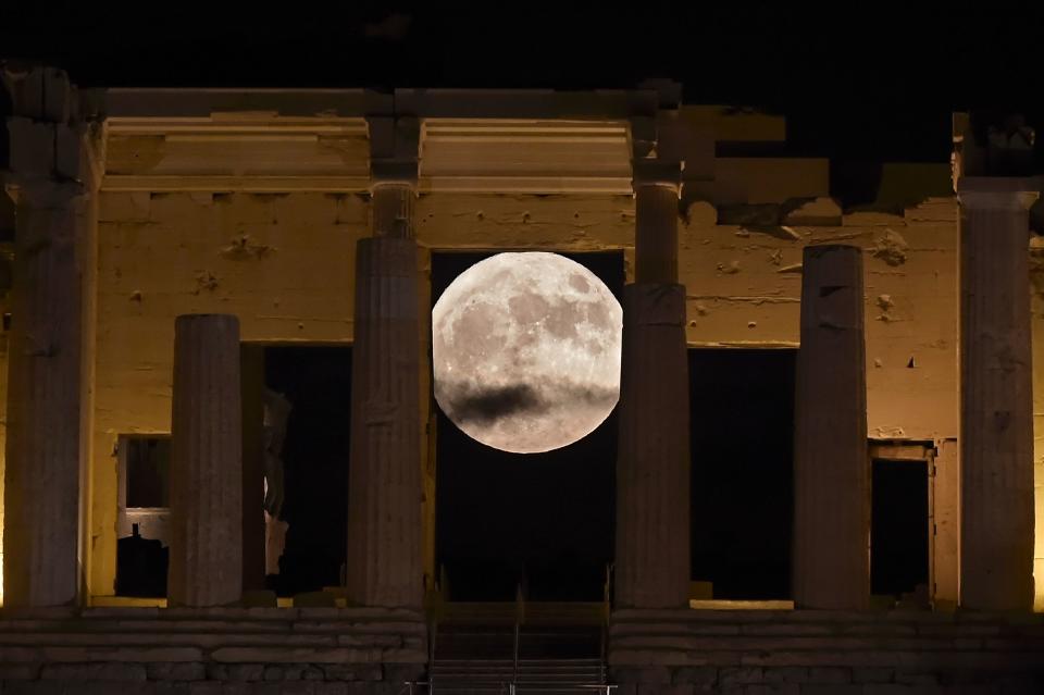 The "supermoon" rises on Monday behind the Propylaea above the Ancient Acropolis hill in Athens.