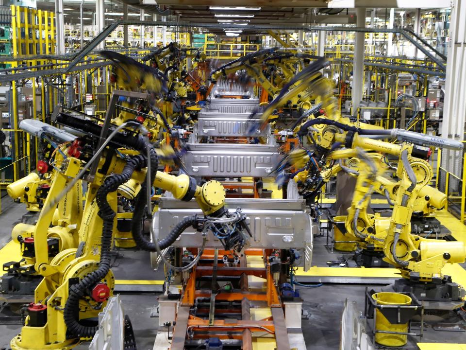 FILE - In this Sept. 27, 2018, file photo robots weld the bed of a 2018 Ford F-150 truck on the assembly line at the Ford Rouge assembly plant in Dearborn, Mich.  U.S. businesses are edging their way toward figuring out how to bring their employees back to work amid the coronavirus pandemic, some more gracefully than others. Detroit-area automakers, which suspended production in March 2020, are now pushing to restart factories as soon as possible. (AP Photo/Carlos Osorio, File)