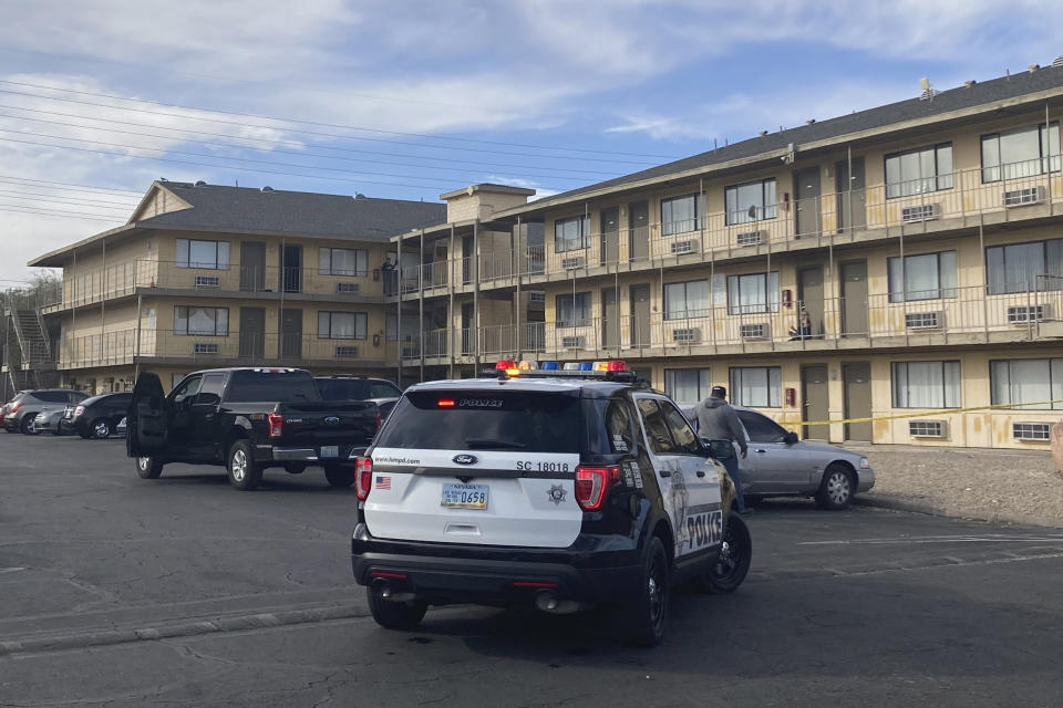 Las Vegas police and residents talk in a parking lot of the Siegel Suites Swenson apartment complex on Friday, March 4, 2022. Authorities say one man was killed and six were wounded in a shooting late Thursday, March 3, 2022 on a third-floor balcony of the low-budget apartment complex east of the Las Vegas Strip. Police said the shooting followed a dispute involving neighbors and that two of the wounded suffered injures described as critical. (AP Photo/Ken Ritter)