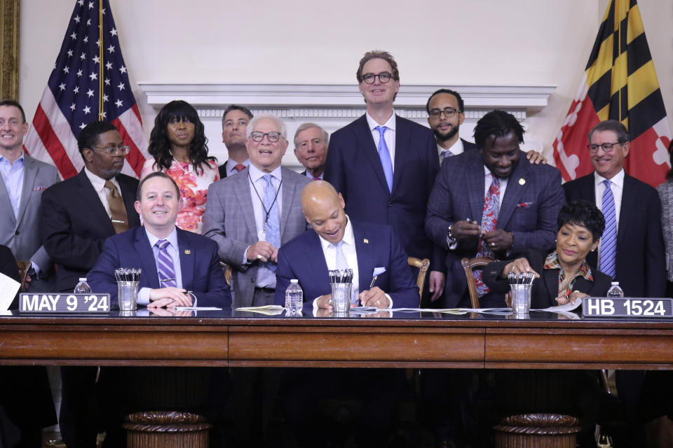 Maryland Gov. Wes Moore signs legislation, Thursday, May 9, 2024, in Annapolis, Md., to rebuild Baltimore's historic but antiquated Pimlico Race Course and transfer the track that is home to the Preakness Stakes, the second leg of horse racing's Triple Crown, to state control. Maryland House Speaker Adrienne Jones is seated right, and Senate President Bill Ferguson is seated left. (AP Photo/Brian Witte)