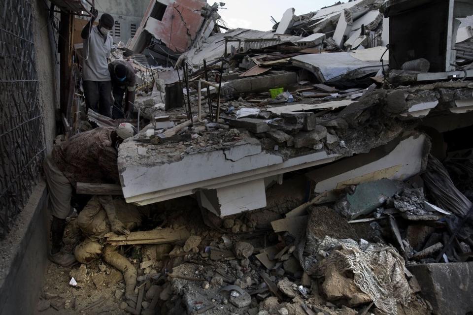 Haitians work to uncover bodies trapped in a collapsed building.