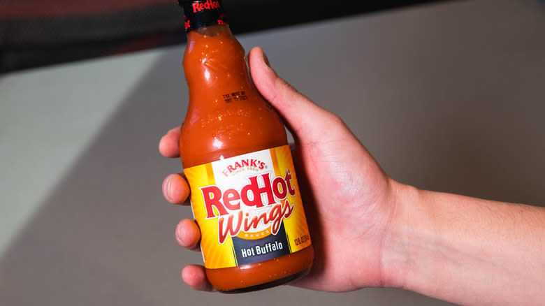 hand holding Frank's RedHot sauce