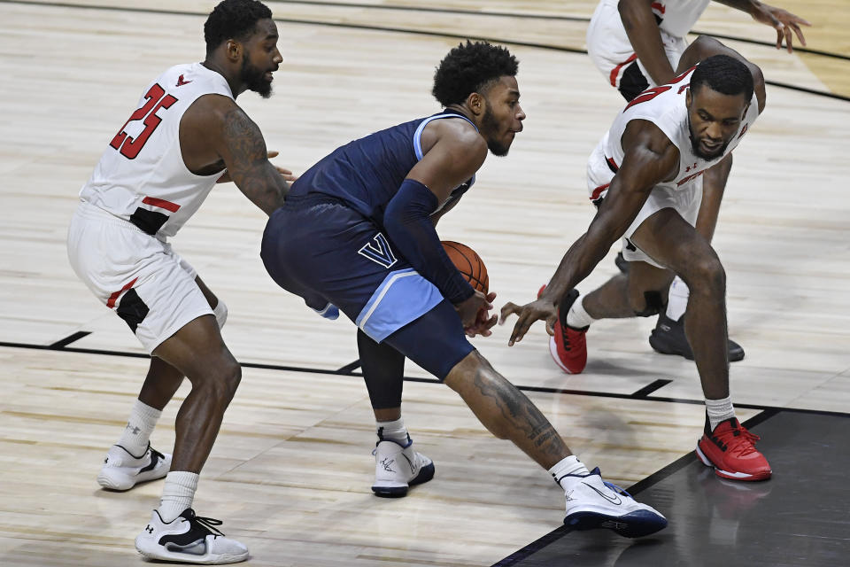 Villanova's Justin Moore, center, keeps the ball from Hartford's Traci Carter, left, and Austin Williams, right, in the second half of an NCAA college basketball game Tuesday, Dec. 1, 2020, in Uncasville, Conn. (AP Photo/Jessica Hill)
