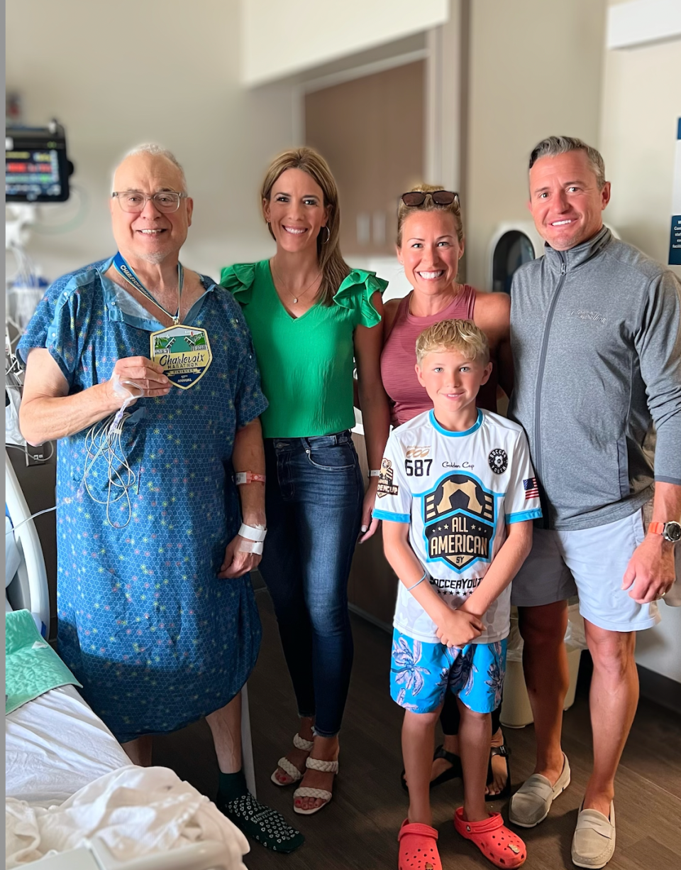 The Charlevoix Marathon director Sharon Suffolk (pink shirt) brings a medal to Richard Mayer (far left) after he suffered a heart attack near the race's finish line on June 17. The cardiac nurse who saved his life, Heather Lewis, (green shirt) was also present.