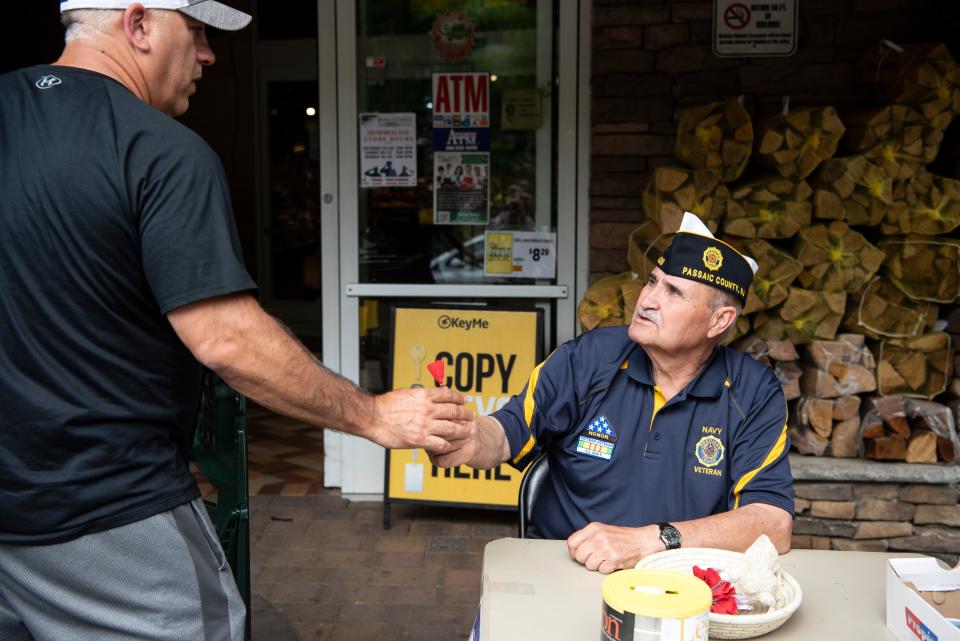 A man accepts a poppy from a Navy veteran after making a donation.