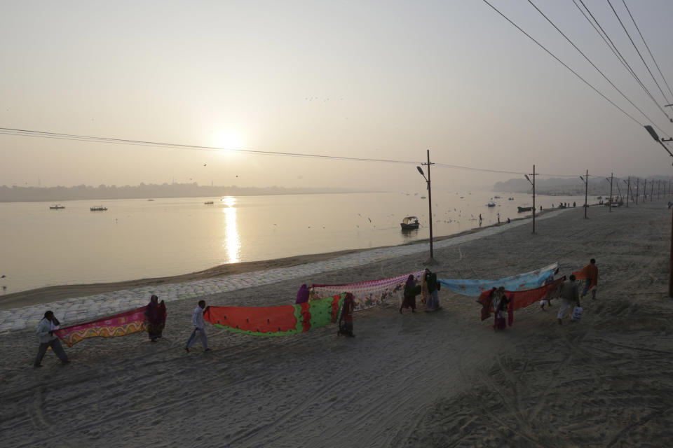 FILE- In this Thursday, Jan. 5, 2017, file photo, Hindu devotees dry their clothes after taking a dip at Sangam, the confluence of rivers Ganges, Yamuna, and mythical Saraswati in Allahabad, India. A court in northern India has granted the same legal rights as a human to the Ganges and Yamuna rivers, considered sacred by nearly a billion Indians. The Uttaranchal High Court in Uttarakhand state ruled Monday, March 20, 2017, that the two rivers be accorded the status of living human entities, meaning that if anyone harms or pollutes the rivers, the law would view it as no different from harming a person. (AP Photo/Rajesh Kumar Singh, File)