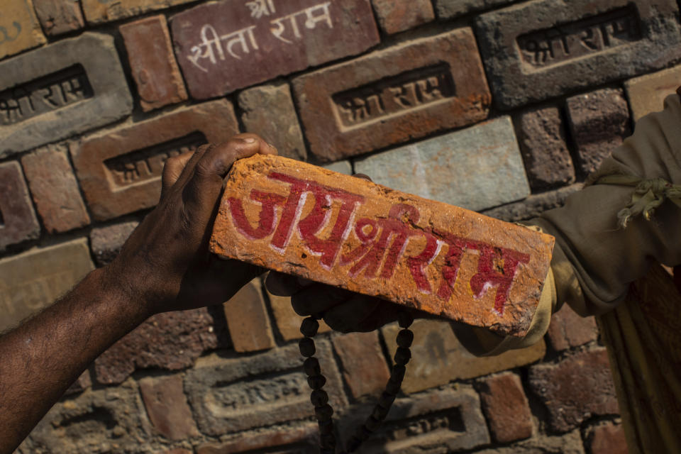 FILE - In this Sunday, Nov. 25, 2018 photo, a man holds a brick reading "Jai Shree Ram" (Victory to Lord Ram) as bricks of the old Babri Mosque are piled up in Ayodhya, in the central Indian state of Uttar Pradesh. State-run broadcaster on Saturday, Nov. 9, 2019, said top court rules for disputed temple-mosque land for Hindus with alternate land to Muslims. Authorities increased security in Ayodhya, 550 kilometers (350 miles) east of New Delhi, and deployed more than 5,000 paramilitary forces to prevent any attacks by Hindu activists on Muslims, who comprise 6% of the town's more than 55,500 people. (AP Photo/Bernat Armangue, File)