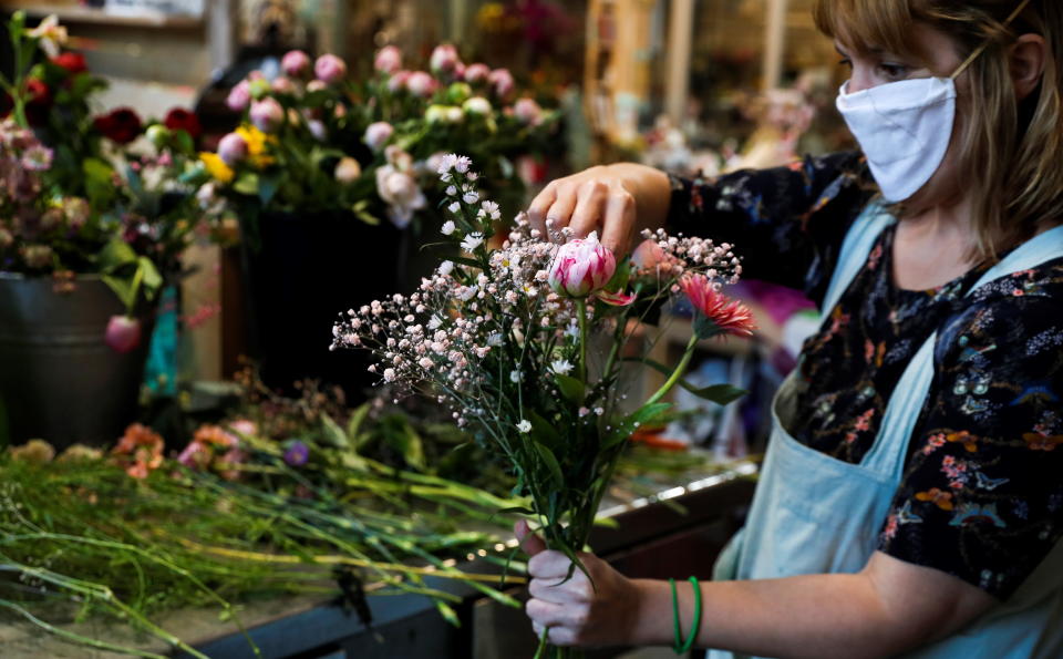 A florist wearing a face mask prepares a flower bouquet for home delivery. Source: AAP