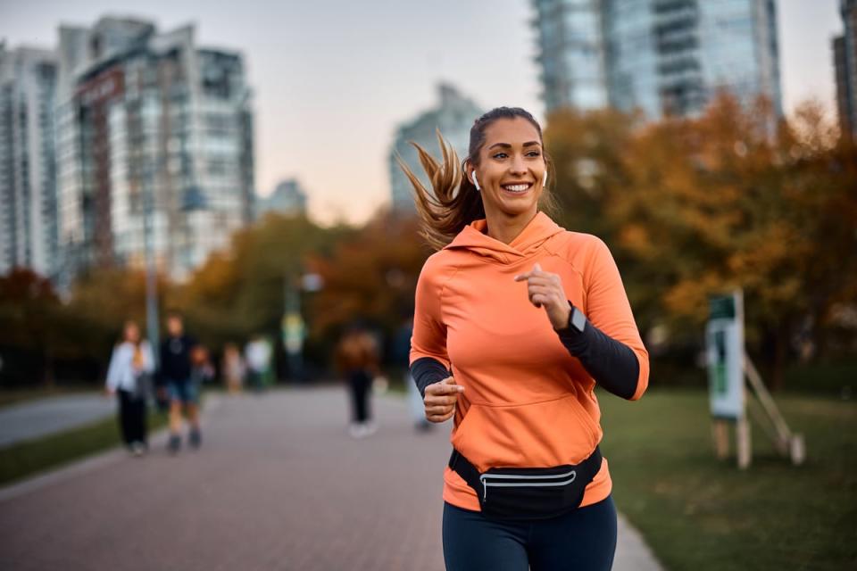 A smiling person running with wireless earbuds. 