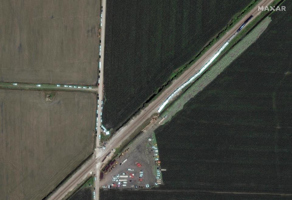 This satellite image provided by Maxar shows an Amtrak train, at right, that derailed a day earlier along the rail line and dozens of cars, heavy lift equipment and rescue vehicles positioned nearby Tuesday near Mendon, Mo.