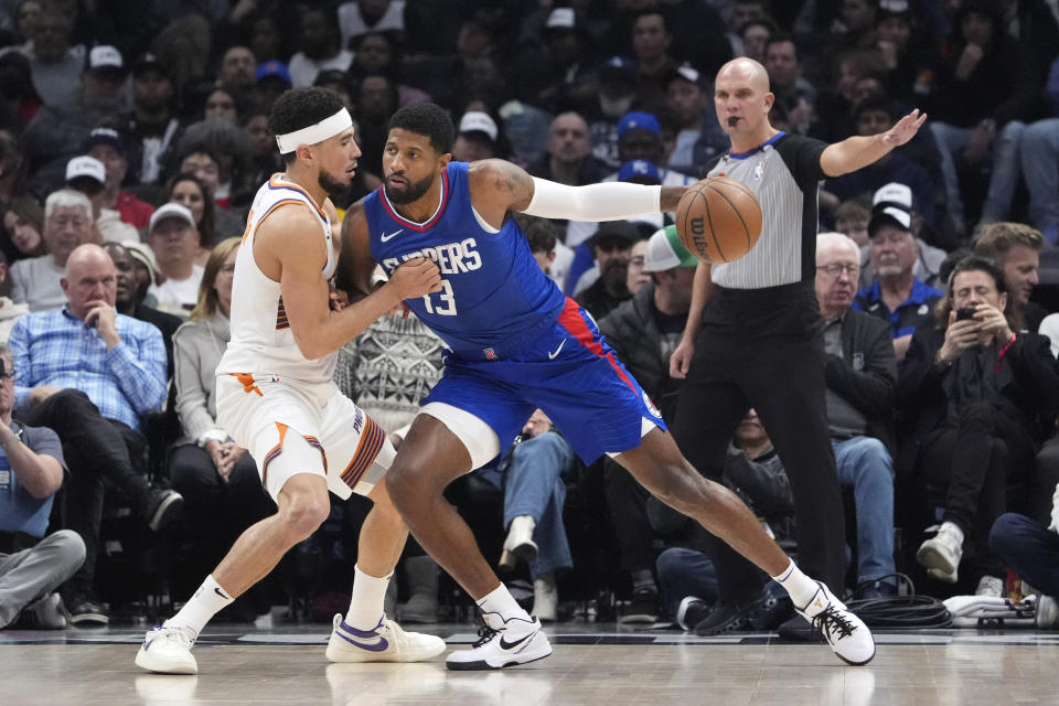 Los Angeles Clippers forward Paul George, center, pushes against Phoenix Suns guard Devin Booker during the first half of an NBA basketball game Monday, Jan. 8, 2024, in Los Angeles. (AP Photo/Mark J. Terrill)