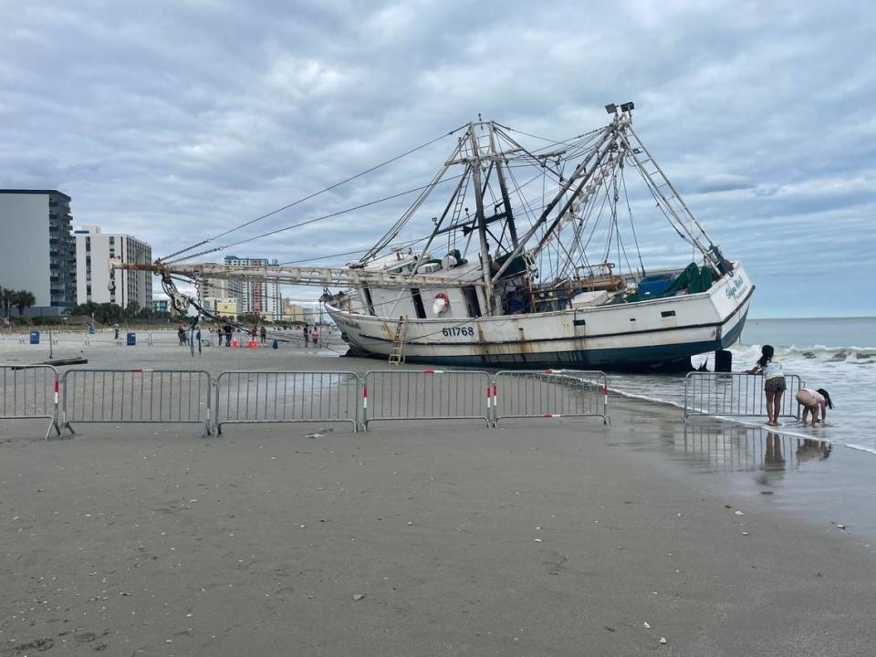 Two children play near the barricades blocking off the Shayna Michelle shrimp trawler, which washed ashore Friday during Hurricane Ian. Oct. 2, 2022.