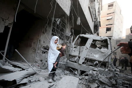 A girl carrying a baby inspects damage in a site hit by what activists said were airstrikes carried out by the Russian air force in the town of Douma, eastern Ghouta in Damascus, Syria January 10, 2016. REUTERS/Bassam Khabieh