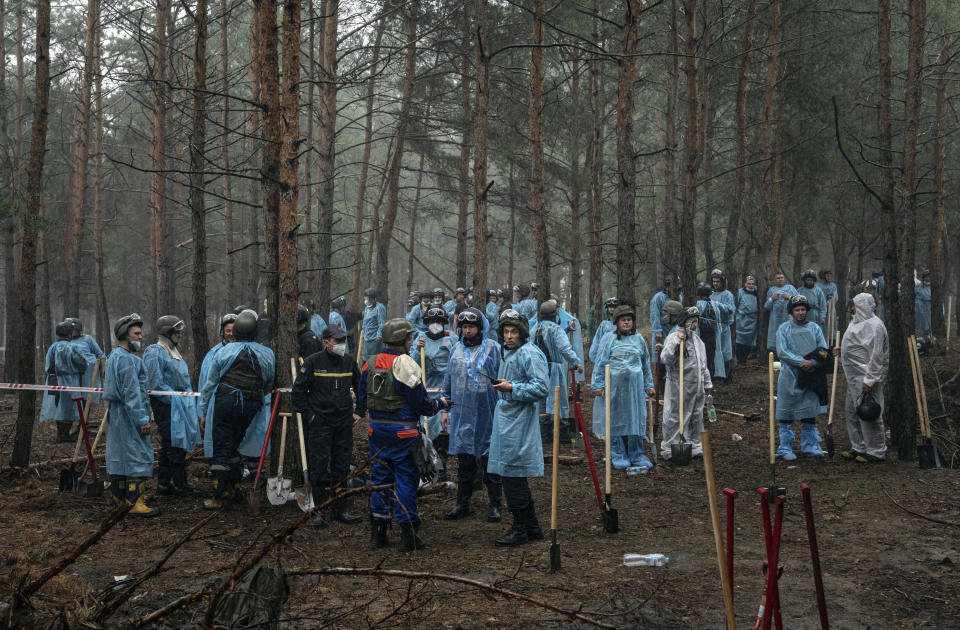 Emergency workers have a rest during the exhumation in the recently retaken area of Izium, Ukraine, Friday, Sept. 16, 2022. Ukrainian authorities discovered a mass burial site near the recaptured city of Izium that contained hundreds of graves. It was not clear who was buried in many of the plots or how all of them died, though witnesses and a Ukrainian investigator said some were shot and others were killed by artillery fire, mines or airstrikes. (AP Photo/Evgeniy Maloletka)