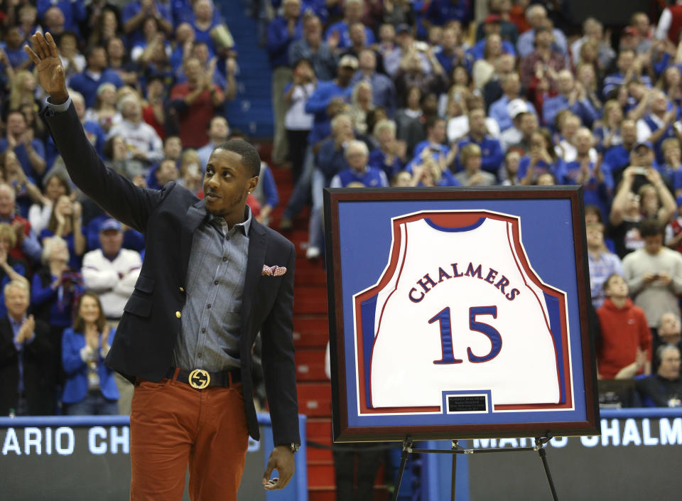 Former Kansas player and current Miami Heat member Mario Chalmers waves to the crowd as his college jersey is retired during a halftime ceremony at an NCAA college basketball game between Texas and Kansas, Saturday, Feb. 16, 2013, in Lawrence, Kan. (AP Photo/Ed Zurga)