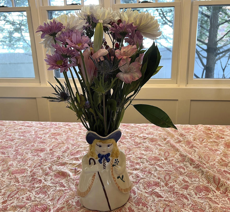 This May 1, 2024 image provided by Jessica Damiano shows a supermarket bouquet of three white chrysanthemums, a lily stem and a single rose embellished with greenery and "filler" flowers on Long Island, New York. Placing flowers in a decorative pitcher or vase is one way to elevate a floral arrangement. (Jessica Damiano via AP)