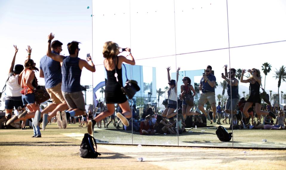 Festival goers jump as they take a selfie in the light installation by Phillip K. Smith III called "Reflection Field" at the Coachella Valley Music and Arts Festival in Indio