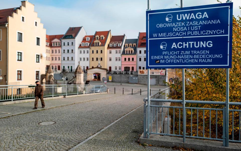 A sign in Polish and German warns visitors entering the Polish city of Zgorzelec from the German city of Goerlitz that face masks must be worn in all public areas in Poland due to the Coronavirus Covid-19 pandemic. Goerlitz, Germany. Nov 26, 2020. - JOHN MACDOUGALL/AFP