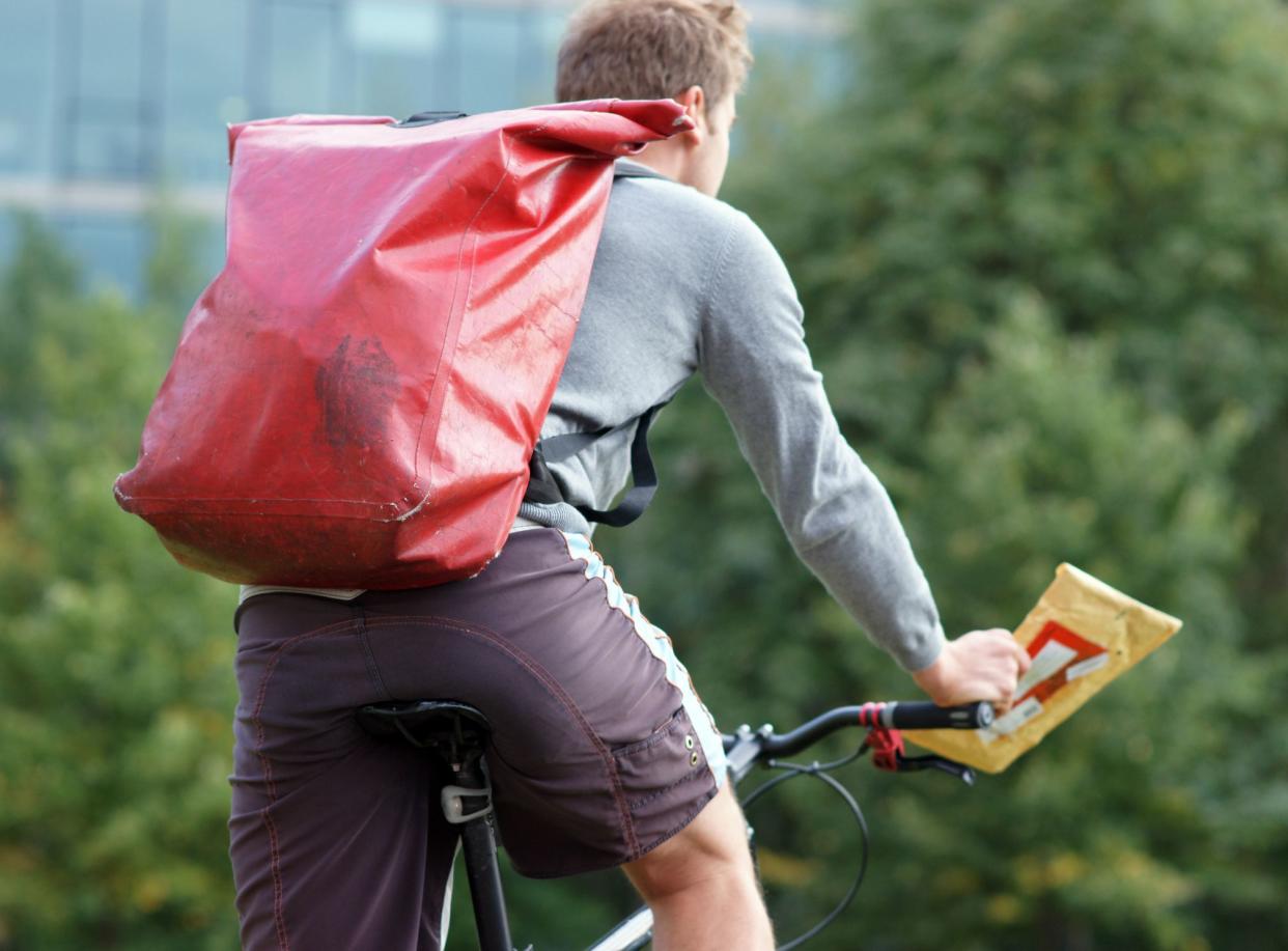 Messenger on bicycle in central Berlin outside in summer on his way to deliver an envelope