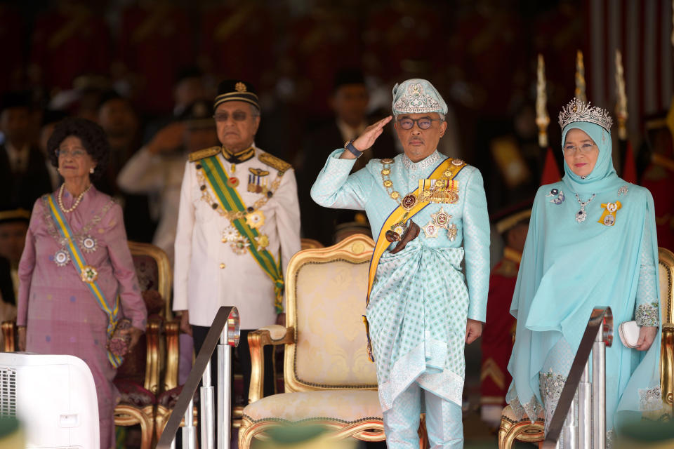 Malaysia's King Sultan Abdullah Sultan Ahmad Shah salutes next to Queen Tunku Azizah Aminah Maimunah, right, Prime Minister Mahathir Mohamad, second from left, and his wife Siti Hasmah during the king's welcome ceremony at Parliament House in Kuala Lumpur, Malaysia, Thursday, Jan. 31, 2019. Sultan Abdullah, ruler of central Pahang state, was named Malaysia's new king, replacing Sultan Muhammad V who abdicated unexpectedly after just two years on the throne. (AP Photo/Yam G-Jun)