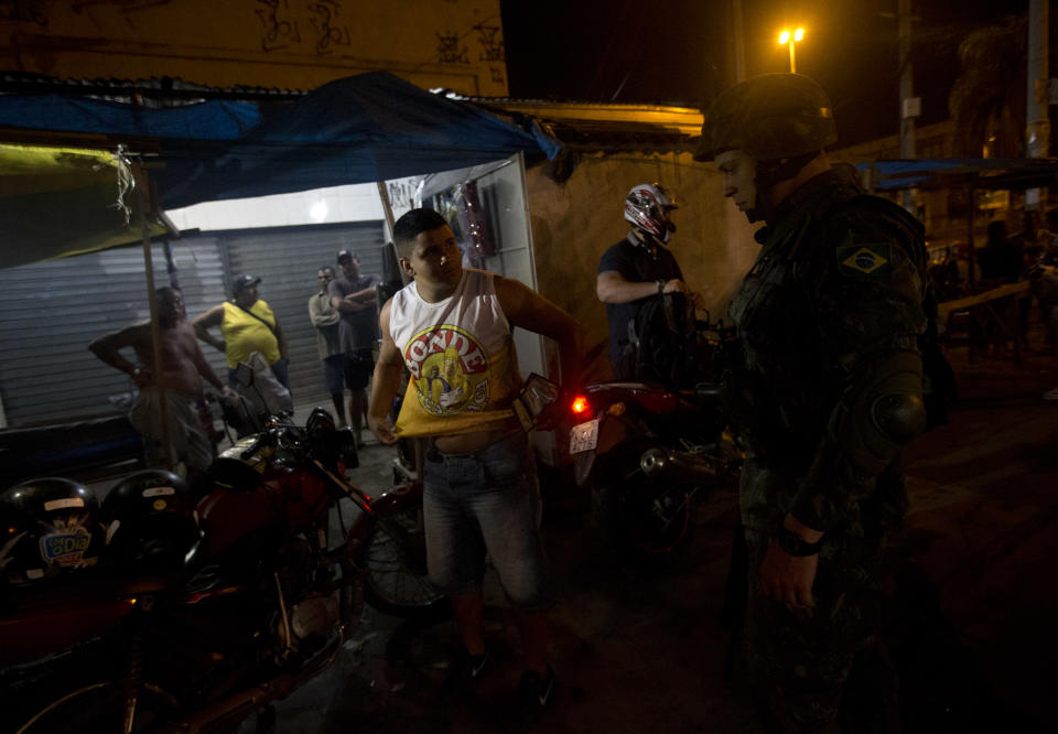An Army soldier searches for guns during an operation to occupy the Mare slum complex in Rio de Janeiro, Brazil, Saturday, April 5, 2014. More than 2,000 Brazilian Army soldiers moved into the Mare slum complex early Saturday in a bid to improve security and drive out the heavily armed drug gangs that have ruled the sprawling slum for decades. (AP Photo/Silvia Izquierdo)