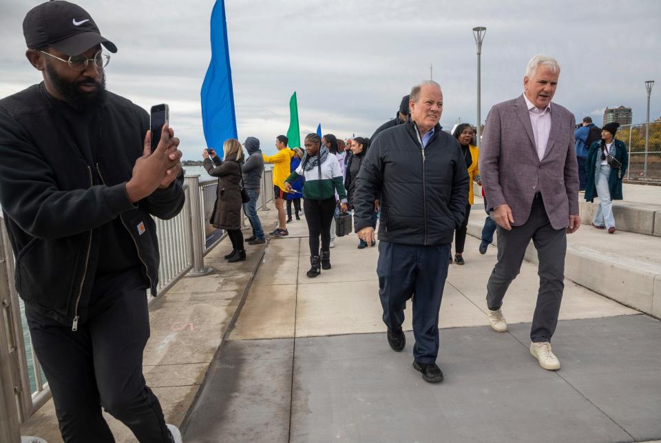 Mayor Mike Duggan, left, walks alongside Matthew Cullen during the Uniroyal Promenade ribbon-cutting ceremony on Detroit's Riverwalk in Detroit on Saturday, Oct. 21, 2023. The new Uniroyal Promenade completes the 3.5 mile-long Riverwalk and provides access to Belle Isle.