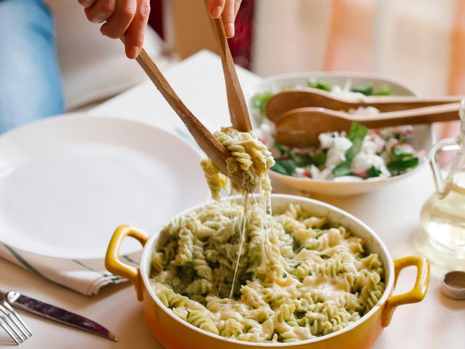 Woman serving pasta with wooden spoons