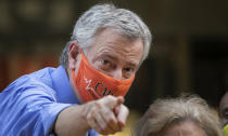 Mayor Bill de Blasio points to the crowd while painting Black Lives Matter on Fifth Avenue in front of Trump Tower, Thursday, July 9, 2020, in New York. (AP Photo/Mark Lennihan)