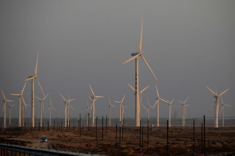 FILE PHOTO: A car drives near wind turbines on a power station near Yumen