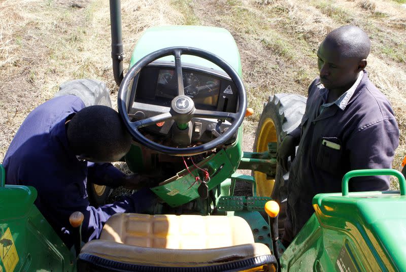 David Kayi, a Hello Tractor engineer, installs an application on a John Deere 5503 tractor, using the Hello Tractor technology that connects farmers with vehicles' owners, at a hay farm in Umande village in Nanyuki