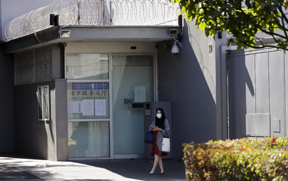 A woman stands in front of the Chinese consulate in Sydney, Wednesday, Sept. 16, 2020. A Chinese-born adviser to an Australian lawmaker has launched a constitutional challenge in Australia's highest court against the nation's laws that ban covert foreign interference on domestic politics. (AP Photo/Rick Rycroft)