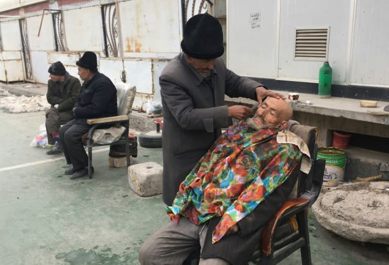 A barber shaves a man outside of a mosque in Kashgar, in China's western Xinjiang region which one of the most policed places on earth